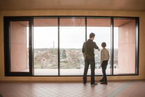 a man and a boy looking out of a large window at Hostel Groeninghe in Kortrijk