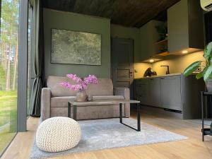 a living room with a couch and a table with purple flowers at Mustika Mirror minivilla saunaga in Kärdla
