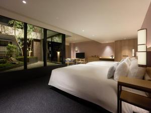 a bedroom with a large white bed and glass walls at Mitsui Garden Hotel Kyoto Sanjo PREMIER in Kyoto