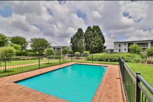 a swimming pool in a yard with a fence at 2Bed in exquisite golf estate! in Roodepoort