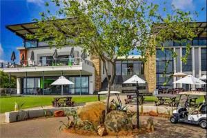 a building with tables and umbrellas in front of it at 2Bed in exquisite golf estate! in Roodepoort