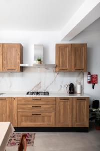 a kitchen with wooden cabinets and a stove at Modern 2BR Stylish Apartment with 2 Balconies - Close to St Julian's & Sliema & Yacht Marina in Tal-Pietà