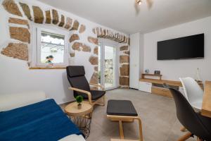 een woonkamer met een tv en een bank en stoelen bij Stone House ZEN in Grižane