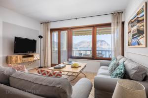 ein Wohnzimmer mit zwei Sofas und einem Fernseher in der Unterkunft Mondello in Terrazza by DomuSicily in Mondello