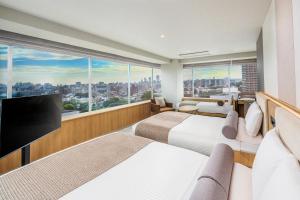 a hotel room with two beds and a flat screen tv at ART HOTEL Nippori Lungwood in Tokyo