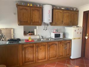 a kitchen with wooden cabinets and a sink and a microwave at Casinha in Quintela