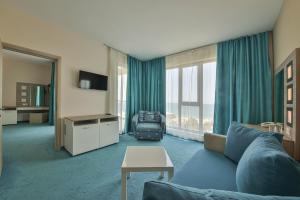 a living room with a blue couch and a large window at Arena Mar Hotel and SPA in Golden Sands
