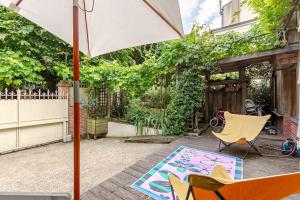 a patio with two chairs and an umbrella and a rug at Maison La campagne à Paris in Le Pré-Saint-Gervais
