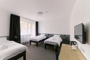 a room with three beds and a table and a tv at RABKA ZDRÓJ Cegielski - pokoje wyremontowane in Rabka-Zdrój