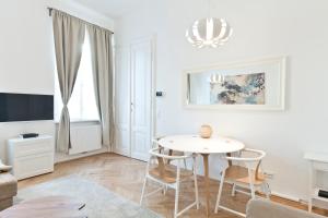 a white living room with a table and chairs at HeyMi Apartments Oper in Vienna