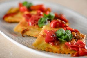 a plate of pizza with tomatoes and basil on it at AC Hotel Genova by Marriott in Genoa