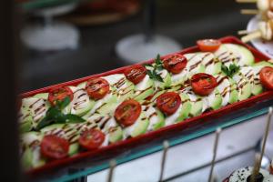 a tray of food with tomatoes on top of it at Arena Mar Hotel and SPA in Golden Sands