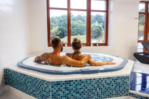 Un uomo e una donna seduti in una vasca da bagno di Pytloun Wellness Hotel Hasištejn a Místo