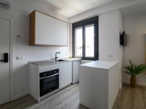 een keuken met witte kasten, een gootsteen en een raam bij Antonella Suites in Fuentes de Andalucía