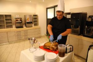 a man preparing a turkey on a table in a kitchen at Arena Mar Hotel and SPA in Golden Sands