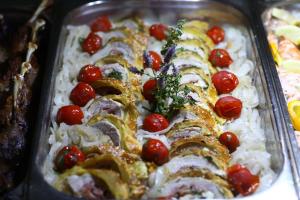 a tray of food with tomatoes on top at Arena Mar Hotel and SPA in Golden Sands