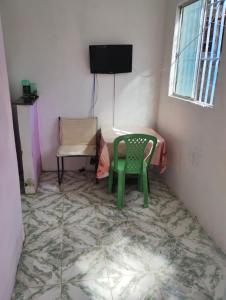 a room with a green chair and a television at Casa 1 quarto amarela praia Cabuçu,Saubara in Saubara