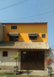 uma casa amarela com uma garagem e duas plantas em Loft praia do pontal, arraial do cabo Rj em Arraial do Cabo
