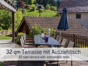 a patio with a table and an umbrella at Enzklösterle in Gompelscheuer
