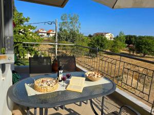 a table with a bottle of wine and baskets on a balcony at Teo's apartment in Fanari