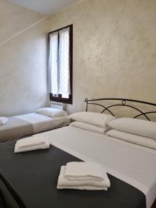 two beds in a room with towels on a table at Rialto House in Venice