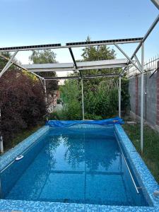 a swimming pool in a backyard with a pergola at Любимый in Cholpon-Ata