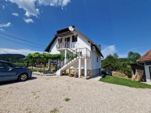 a white house with a car parked in the driveway at House Luketić in Rastovača