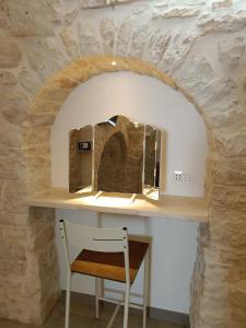 a dressing table with a chair under a stone wall at Domus Mea in Alberobello +18 photos