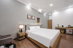 a bedroom with a large white bed and a chair at A25 Hotel - 185-187 Lò Đúc in Hanoi