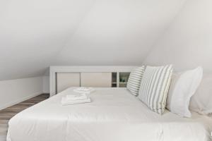 a large white bed with white sheets and pillows at Villa Camelia by Homie in Santo António