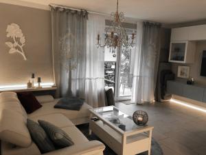 a living room with a white couch and a chandelier at Strandstraße H3W2-EG Kölpinsee in Loddin