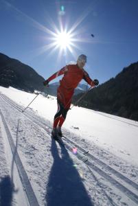een man op ski's in de sneeuw met de zon bij Apart Bergzeit in Nauders