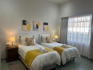 two beds in a white room with a window at Cherry Lane Guest House in Ficksburg