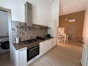 a kitchen with white cabinets and a stove top oven at casa di Lorenzino in Carloforte