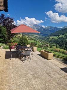 a table and chairs under an umbrella with a view at Pierre de Famille in Manigod