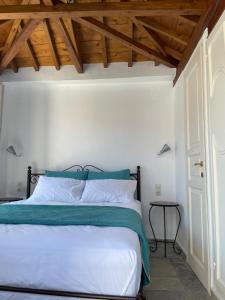 a bedroom with a bed with white sheets and a wooden ceiling at Spitaki in Skopelos Town