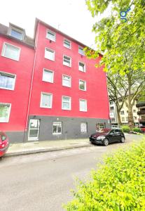 een rood gebouw met een zwarte auto ervoor geparkeerd bij BEGE APARTMENTS WorkStay Lodge in Essen