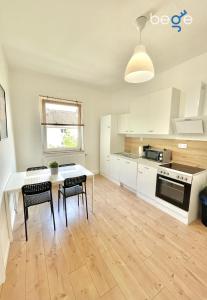 een keuken met witte kasten en een tafel en stoelen bij BEGE APARTMENTS WorkStay Lodge in Essen +7 foto's