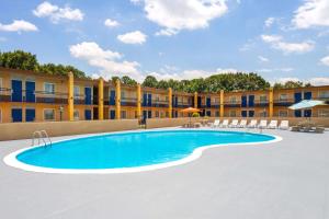 a pool at a hotel with chairs and a building at Days Inn by Wyndham Shelby in Shelby