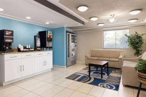 a waiting room with a couch and a tv at Day's Inn & Suites by Wyndham Indianapolis Airport East in Indianapolis