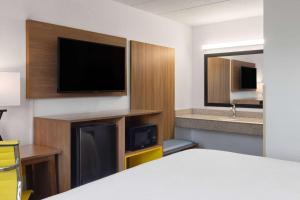 a hotel room with a bed and a flat screen tv at Day's Inn & Suites by Wyndham Indianapolis Airport East in Indianapolis