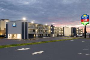 a large building with a sign in front of it at Day's Inn & Suites by Wyndham Indianapolis Airport East in Indianapolis