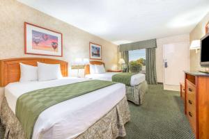 ein Hotelzimmer mit zwei Betten und einem Fernseher in der Unterkunft Days Inn & Suites by Wyndham Albuquerque North in Albuquerque