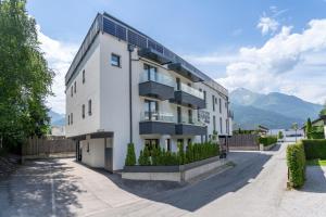 biały budynek apartamentowy z górami w tle w obiekcie Aparthotel Zell am See (Contactless Check-In) w mieście Zell am See