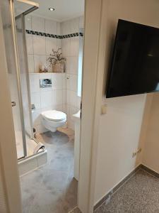 ein Bad mit einem WC und einen TV an der Wand in der Unterkunft Standardzimmer nahe Messe und Airport in Düsseldorf