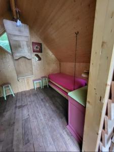 a room with a pink bed in a wooden house at Cabane insolite in Saint-Victor-de-Morestel