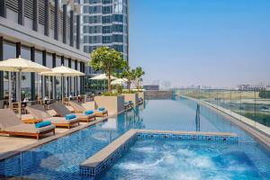 a swimming pool with chairs and umbrellas on a building at Embassy Suites By Hilton Dubai Business Bay in Dubai