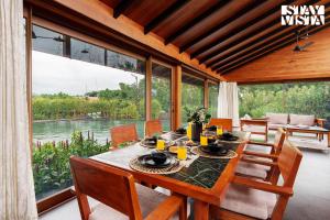 ナーシクにあるStayVista at Stonescape Villa with Pool, Lawn & Mountain Viewのテーブルと椅子と大きな窓のあるダイニングルーム