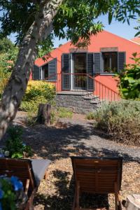 ein orangefarbenes Gebäude mit zwei Bänken davor in der Unterkunft Casa da Raposeira by An Island Apart in Calheta