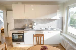 a kitchen with white cabinets and a sink and a table at Bauerhof Kleingarn - Bauernhus 11 in Sulsdorf auf Fehmarn